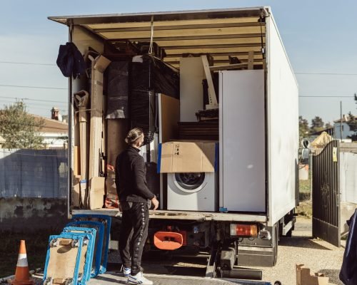 Full shot of a worker observes the arrangement of the packages inside a moving truck