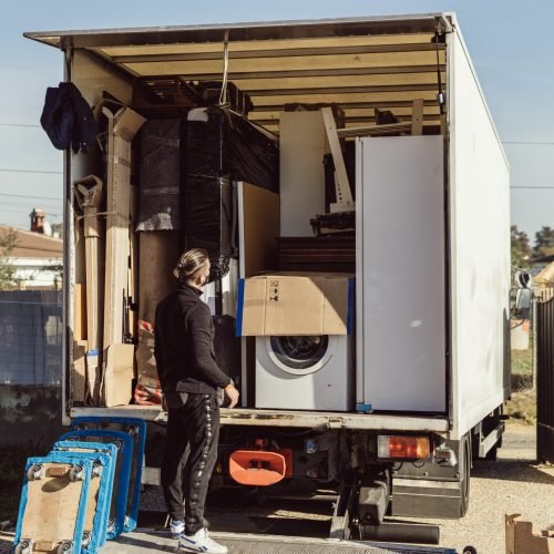 Full shot of a worker observes the arrangement of the packages inside a moving truck