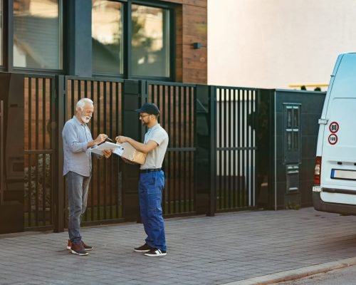 Happy senior customer signing to a courier for home delivery.