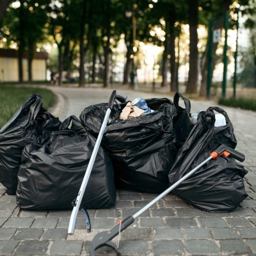 Full plastic trash bags in park, volunteering motivator. Ecological restoration, eco lifestyle, ecology care, environment cleaning concept