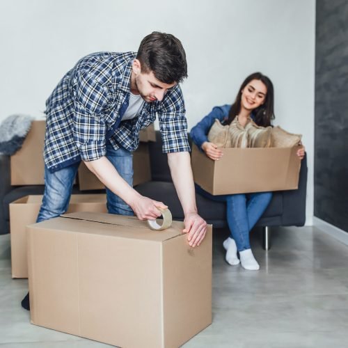 Happy young couple packing cardboard boxes during relocation!