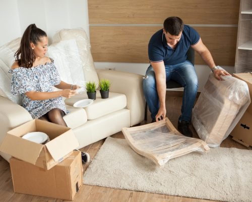 Young couple Moving in new home and unpacking carboard boxes.Almost done moving in.
